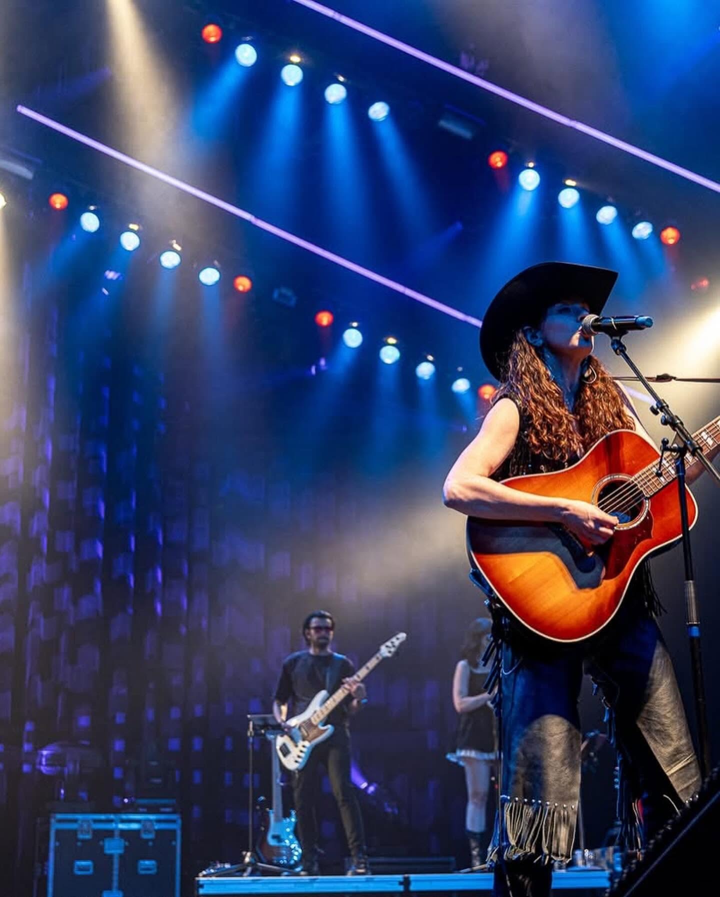 Melissa Endean on stage with guitar, band in background