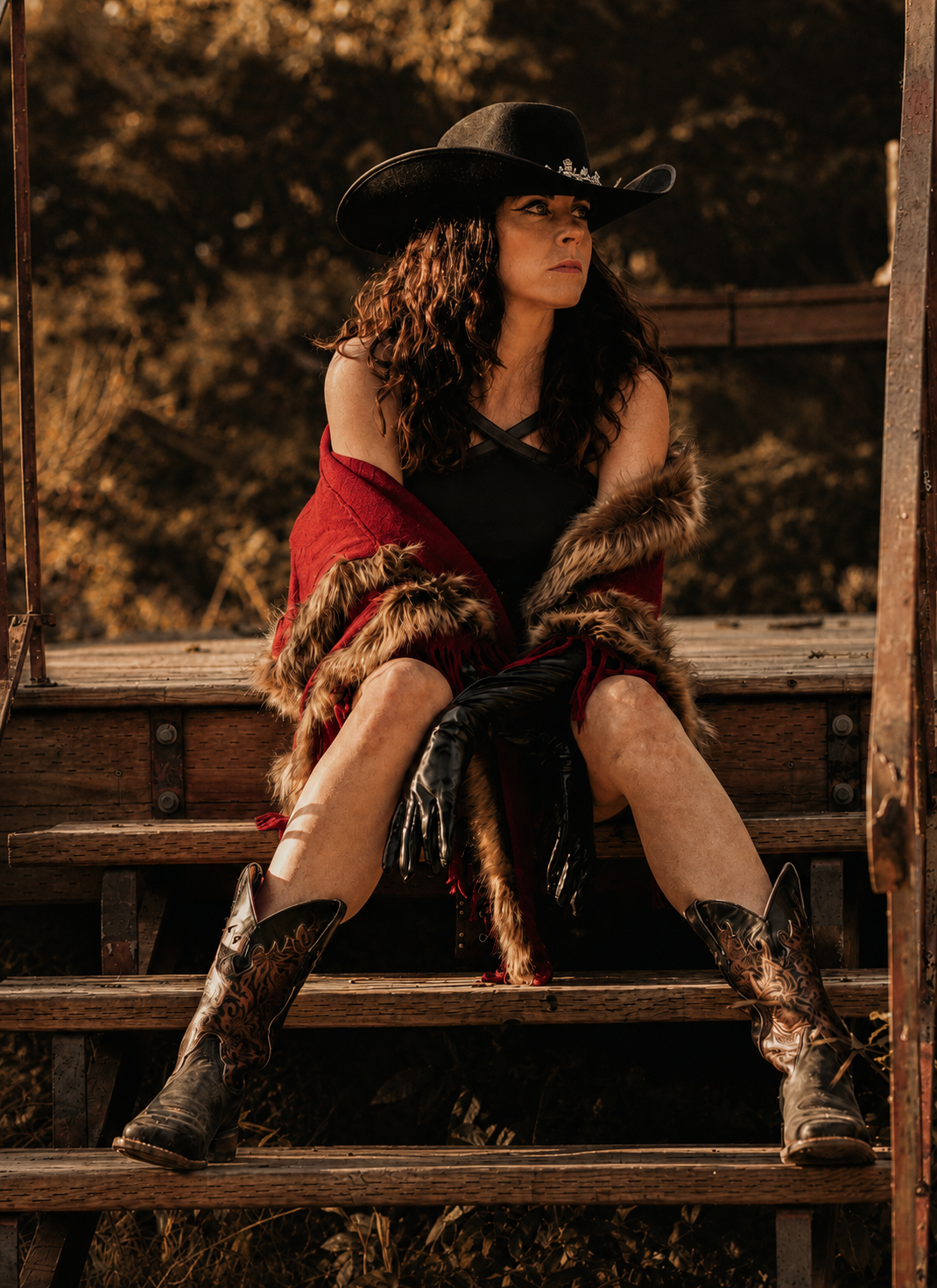 Melissa Endean seated on wooden stairs in cowboy boots and fur wrap